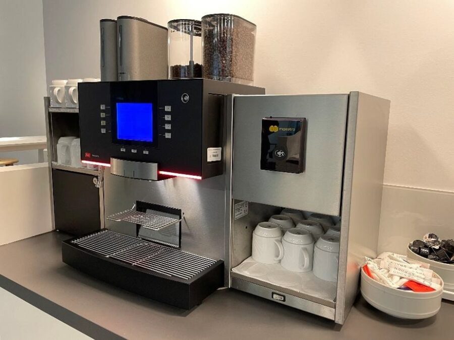Moderne Kaffeemaschine mit Touchscreen, Bohnenbeh&auml;lter und Tassenablage in einer minimalistischen K&uuml;chenumgebung.