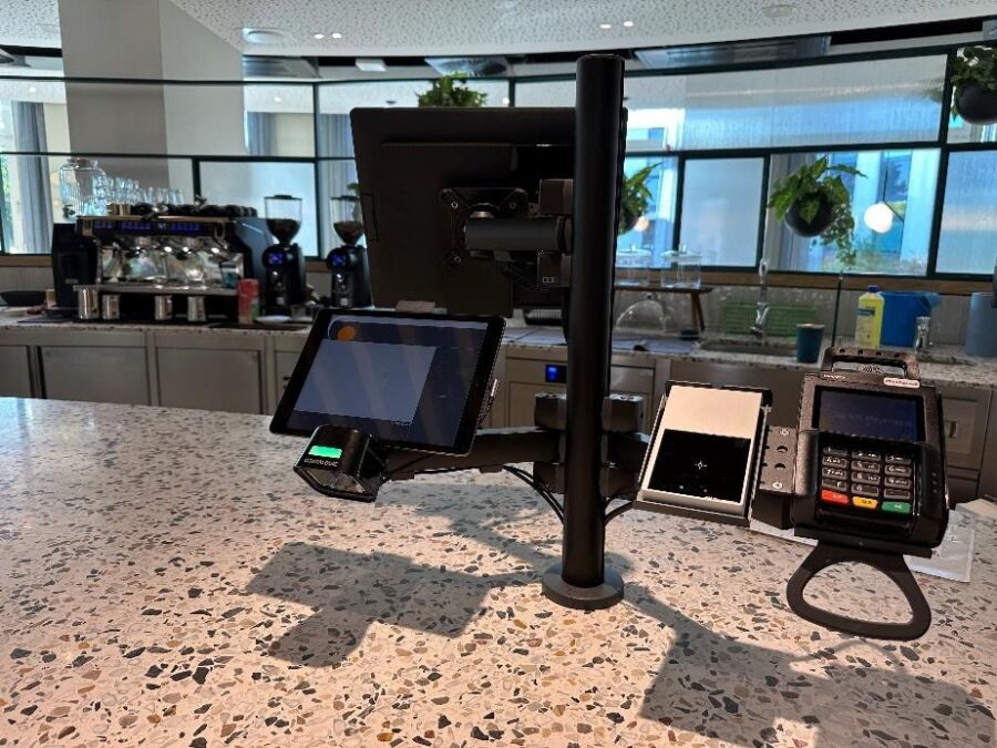 Moderne Kasse mit mehreren Bildschirmen und Zahlungsger&auml;ten auf einer Theke in einem Caf&eacute;.