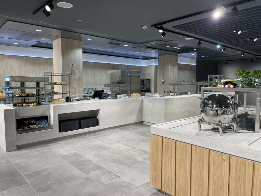 Moderne, helle K&uuml;chenumgebung mit einer gro&szlig;z&uuml;gigen, offenen Essensausgabe und eleganten Holz- und Steinoberfl&auml;chen.