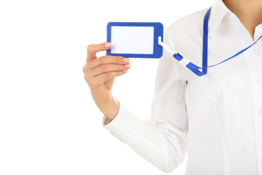 Eine Hand h&auml;lt ein blaues Namensschild mit einer wei&szlig;en Fl&auml;che, getragen an einem blauen Band.